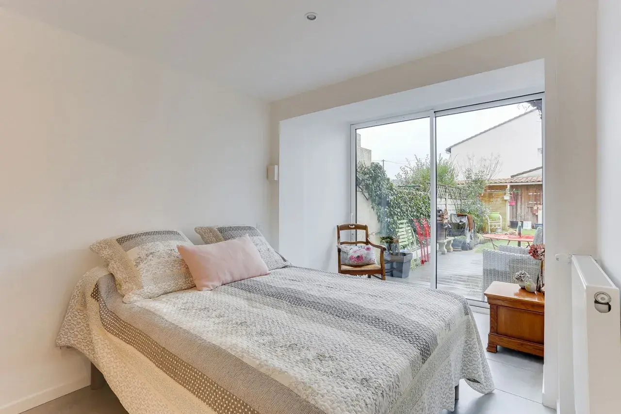 Chambre lumineuse avec vue sur jardin, résultat d'une belle idée : transformer un garage en habitation. Lit douillet, mobilier cosy.