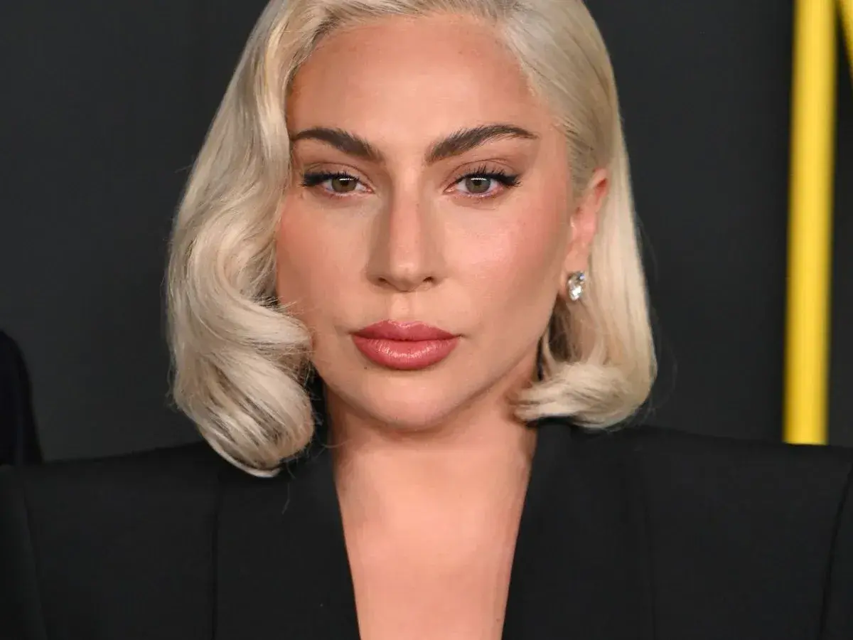 Lady Gaga, z blond włosami i makijażem, w czarnej marynarce. Czy Lady Gaga ma dziecko? To pytanie nurtuje fanów.