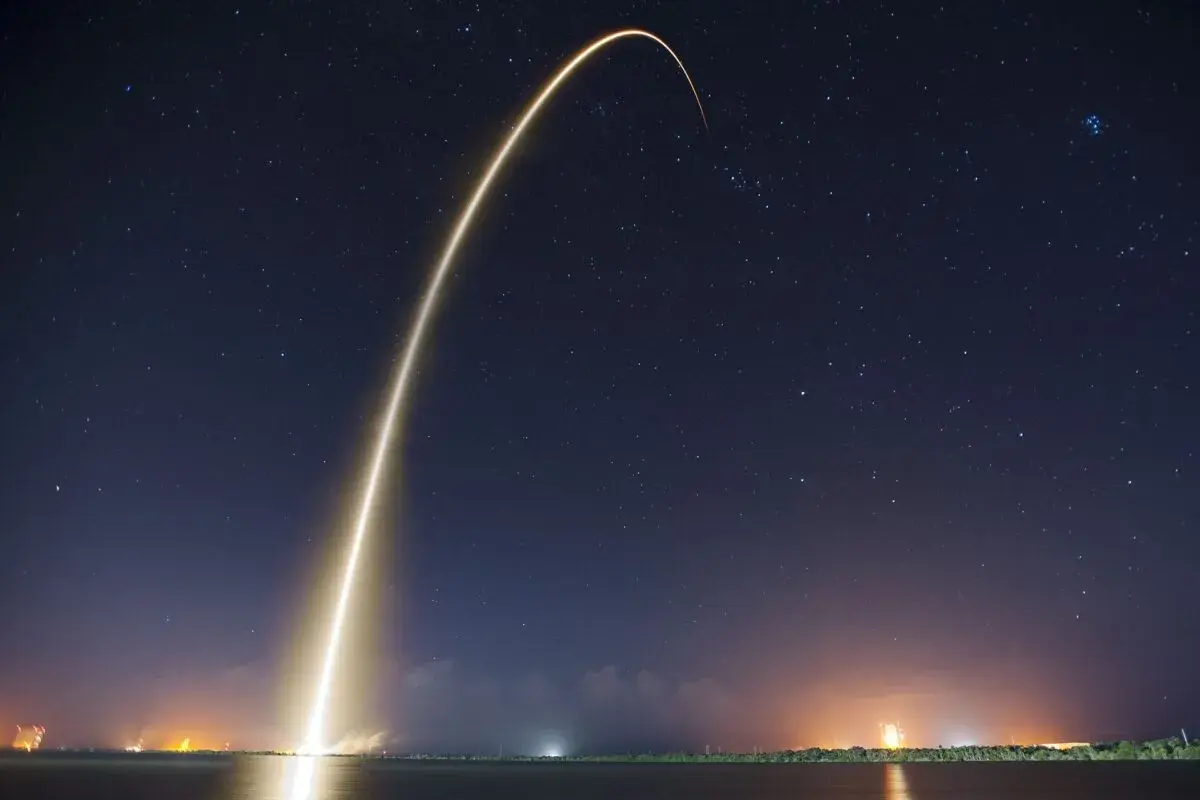 Jasny ślad rakiety wznosi się na nocne, gwieździste niebo, symbolizując start Starlink Elona Muska.