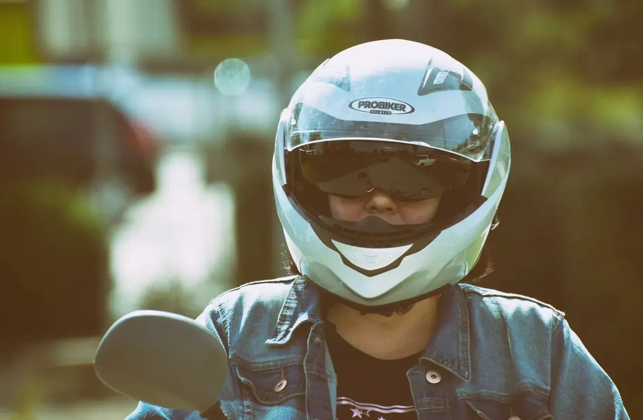 Motociclista con casco jet, che offre una visione chiara, a differenza di un casco demi jet. Indossa giacca di jeans.