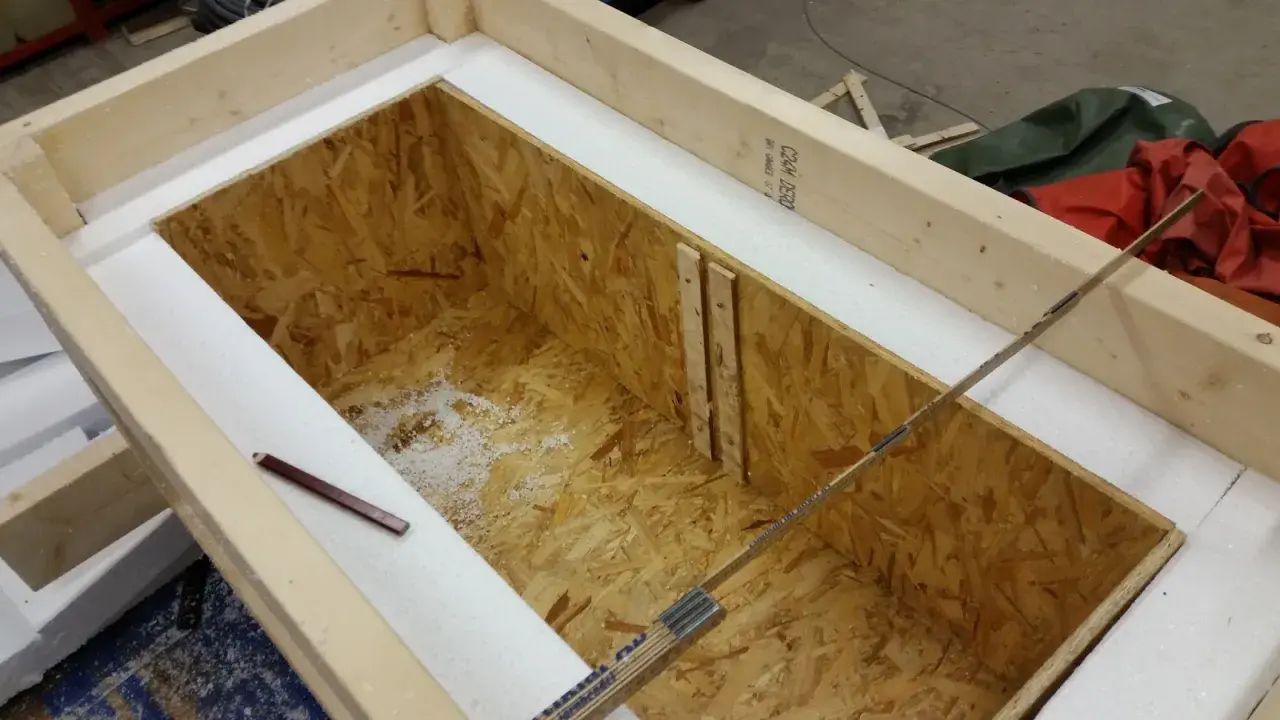 Wooden frame with OSB interior, insulated with white foam. A pencil and ruler are visible.