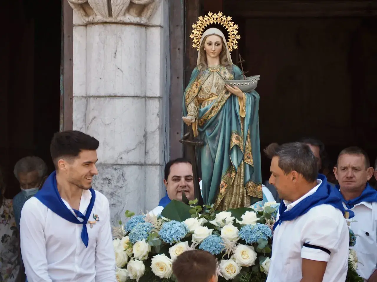 Procesión de la Virgen de la Guía, con hombres portando la imagen adornada con flores.