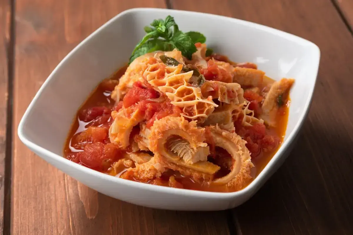 Trippa in umido con pomodoro e basilico, un piatto saporito che contiene ingredienti semplici ma gustosi.