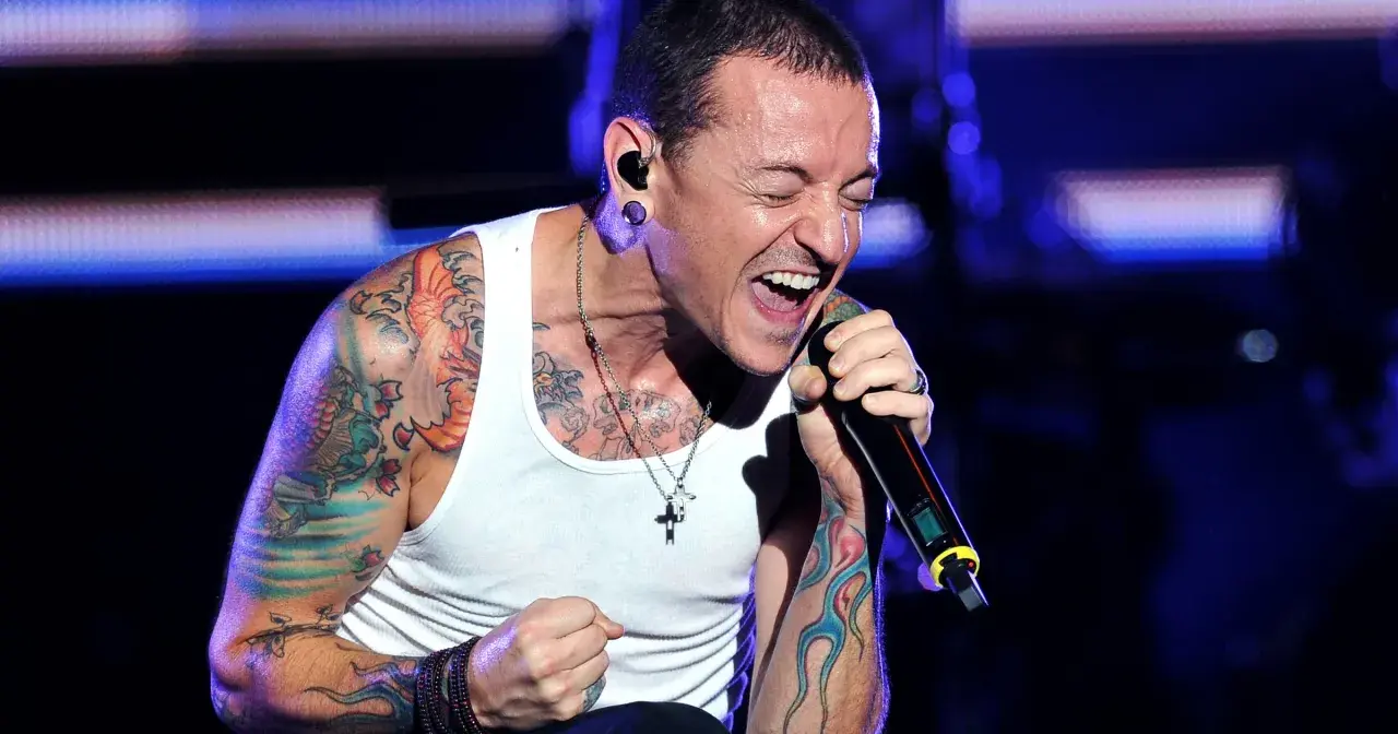 Chester Bennington, wokalista zespołu, śpiewa z pasją na koncercie. Jego ramiona pokryte są kolorowymi tatuażami.