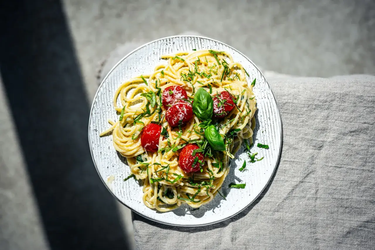 Spaghetti mit cremigem Pesto Trapanese, garniert mit Kirschtomaten und Basilikum.