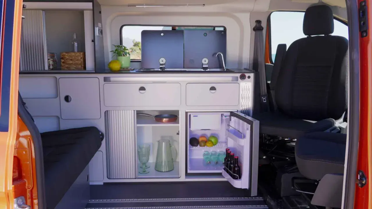 Aménagement astucieux de la soute d'un camping-car : cuisine fonctionnelle, réfrigérateur et rangements optimisés pour un voyage serein.