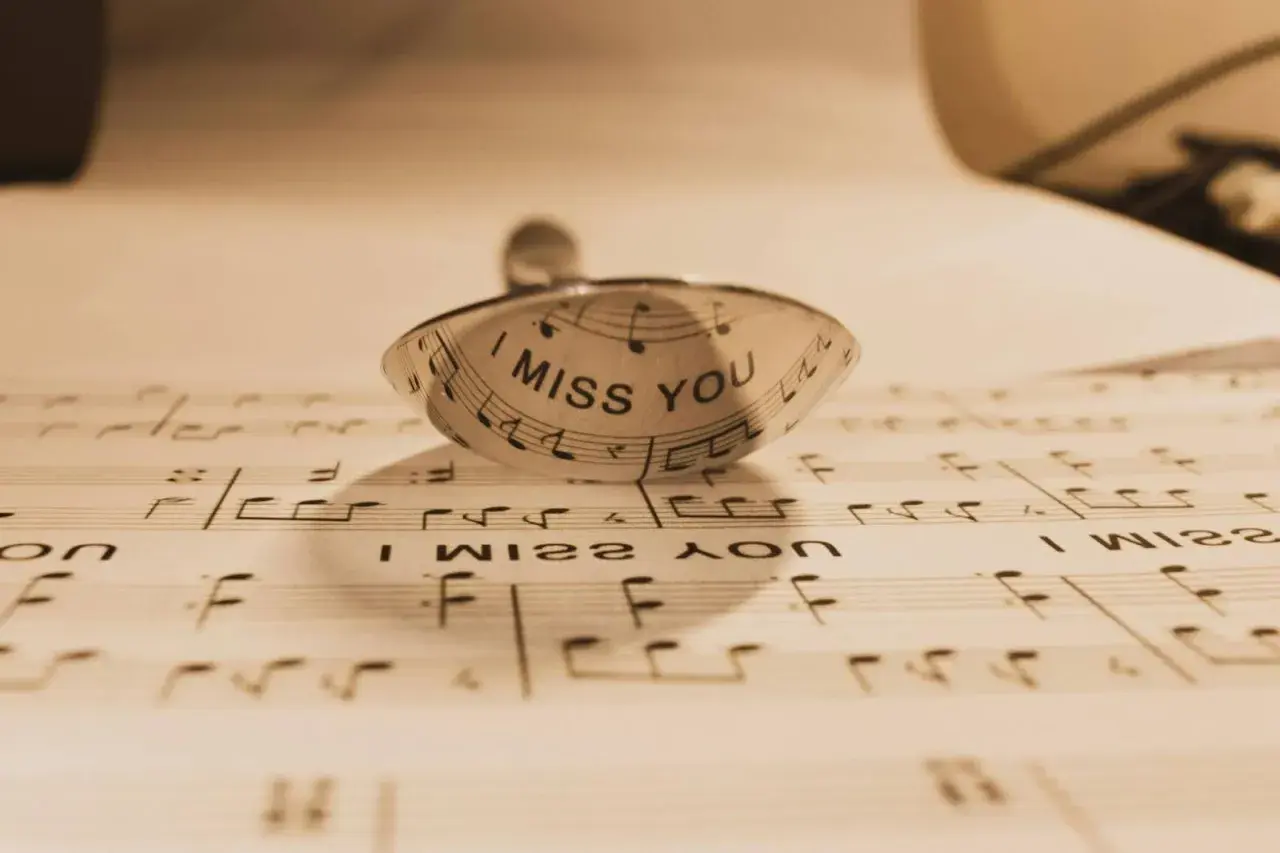Un anillo con la frase "I MISS YOU" sobre partituras. Un detalle que evoca indirectas y frases de te echo de menos.