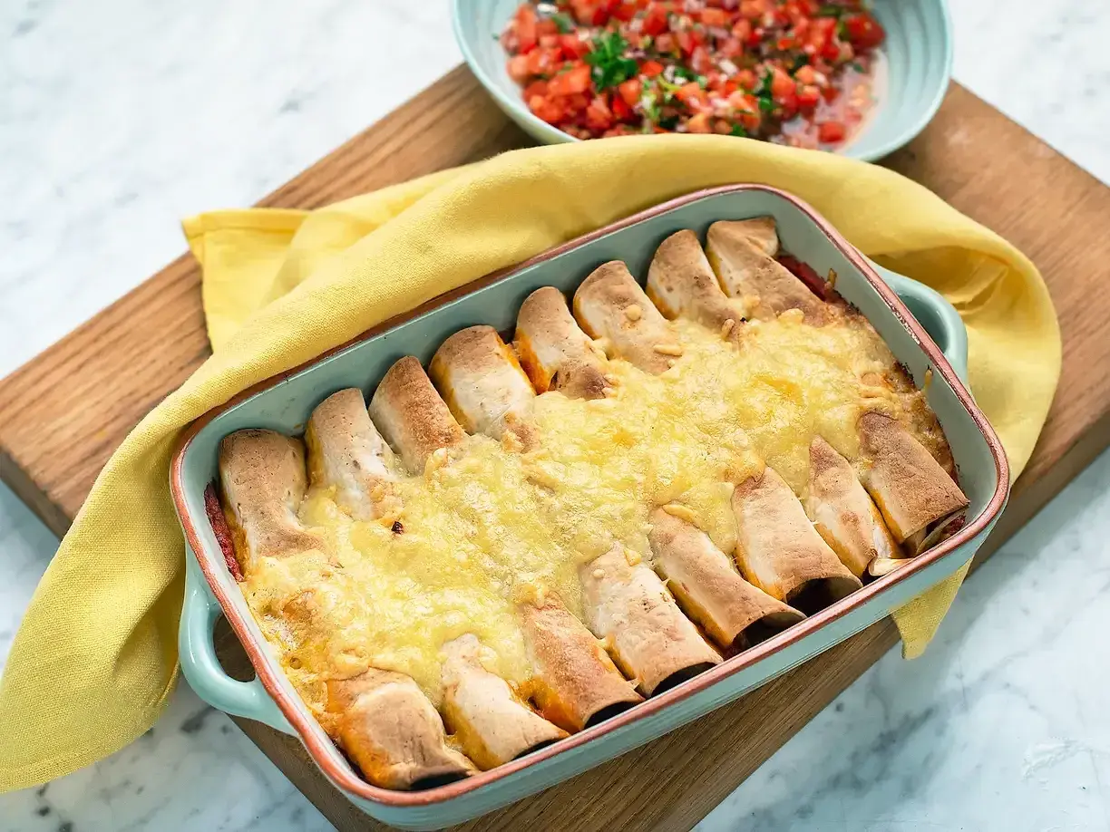 Enchiladas kyckling i ugnsform, gyllene och gratinerade med ost. Serveras med en fräsch tomatsalsa.