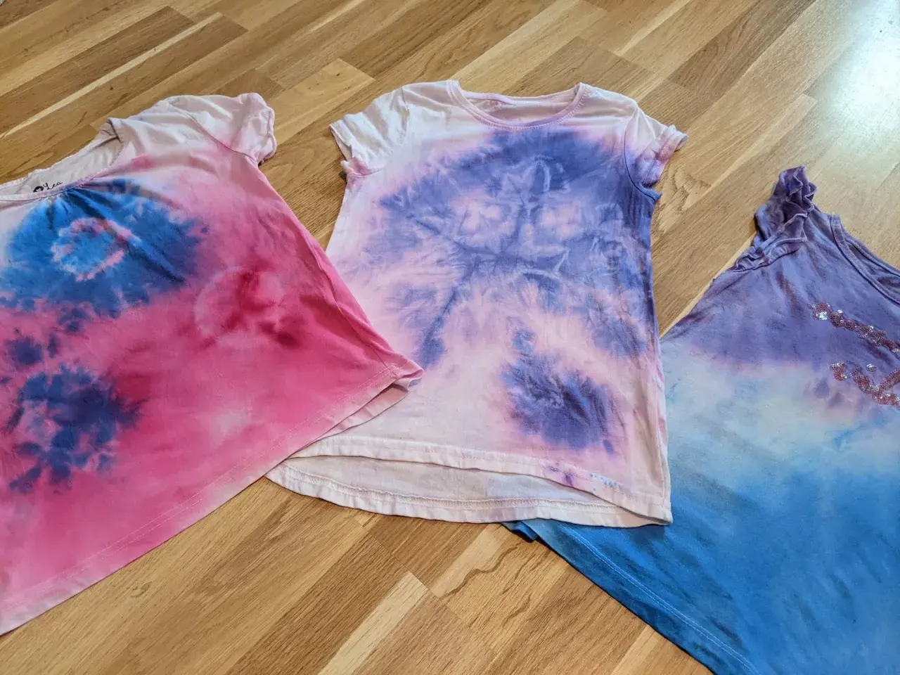 Batik-Shirts in Rosa, Lila und Blau, perfekt für das Batiken mit Kindern. Ein Spaß für die ganze Familie!