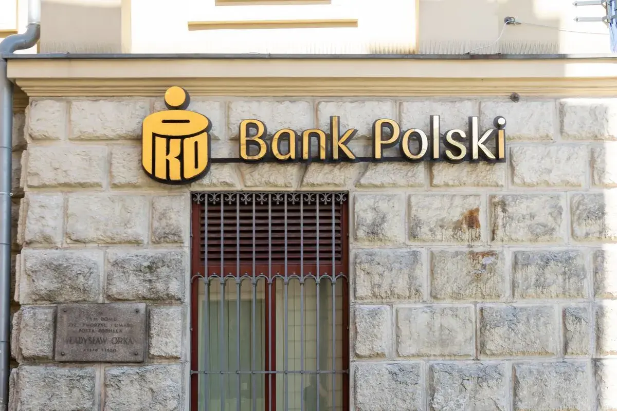 PKO Bank Polski oferuje pko kredyt hipoteczny bez wkładu własnego. Złote logo banku na kamiennej fasadzie.