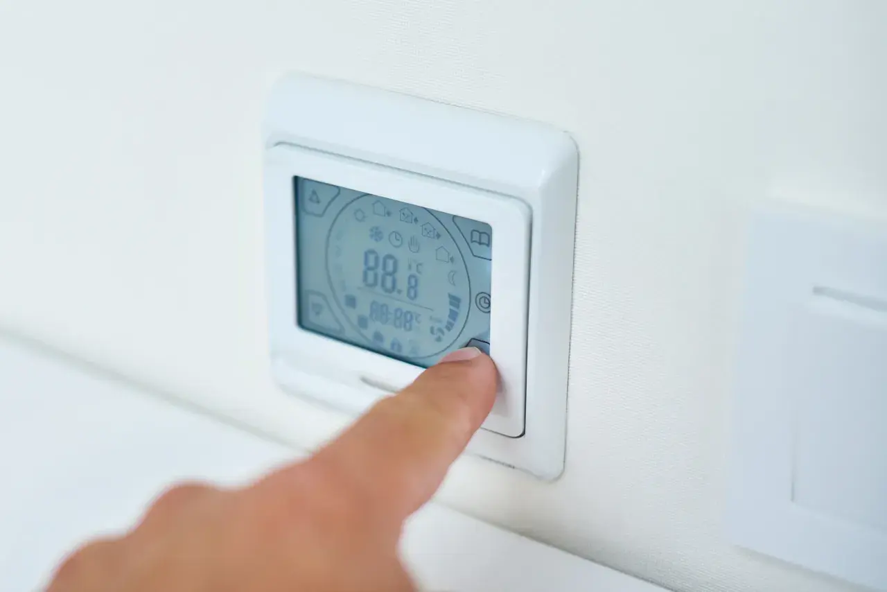 Palec naciska przycisk termostatu, ustawiając idealną temperaturę pieca gazowego.