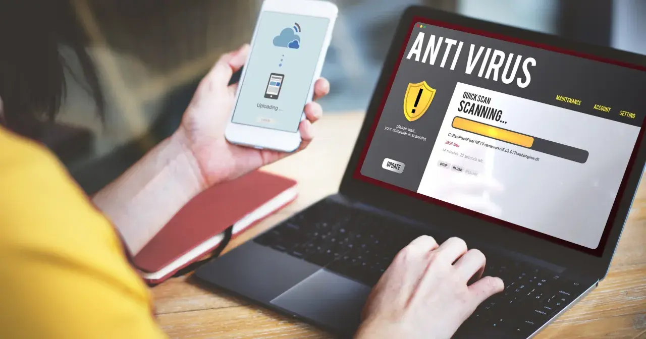 Osoba korzysta z laptopa z programem antywirus free, który skanuje komputer. Na telefonie widnieje komunikat o przesyłaniu danych.