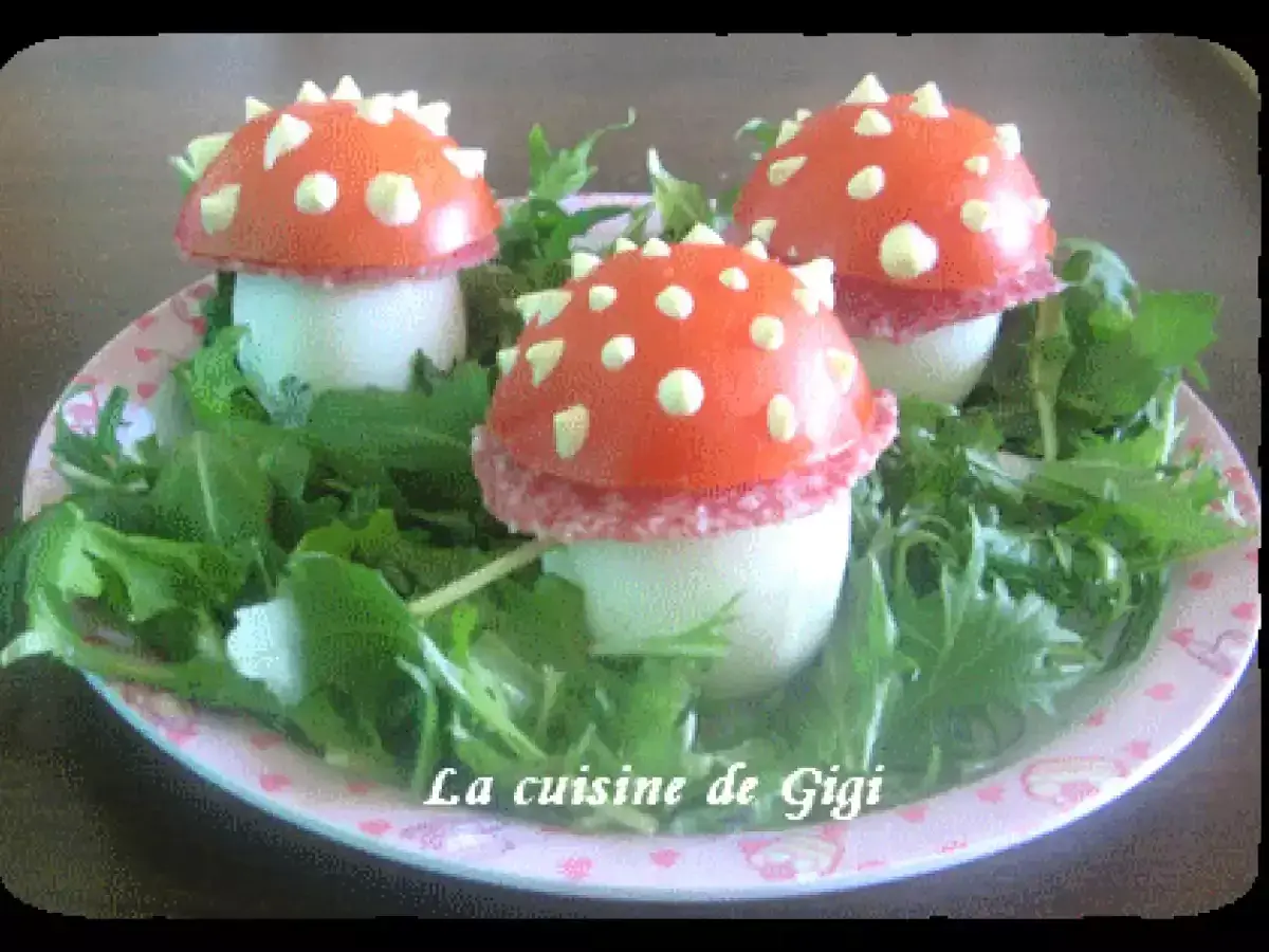 Trois adorables champignon œuf, décorés de tomate et de points blancs, reposent sur un lit de verdure.