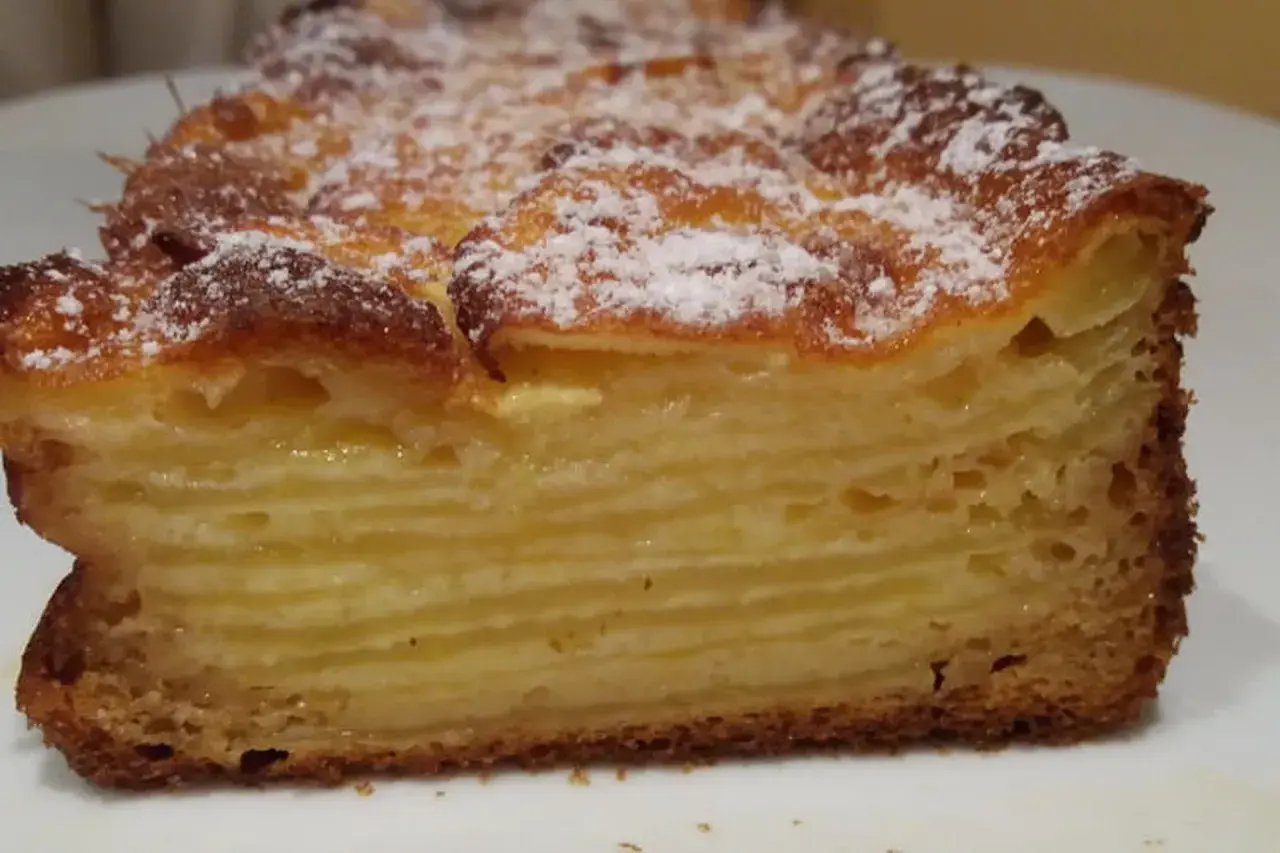 Une tranche de gâteau aux pommes, avec des couches fines et dorées, saupoudrée de sucre glace. Un délice invisible aux pommes.
