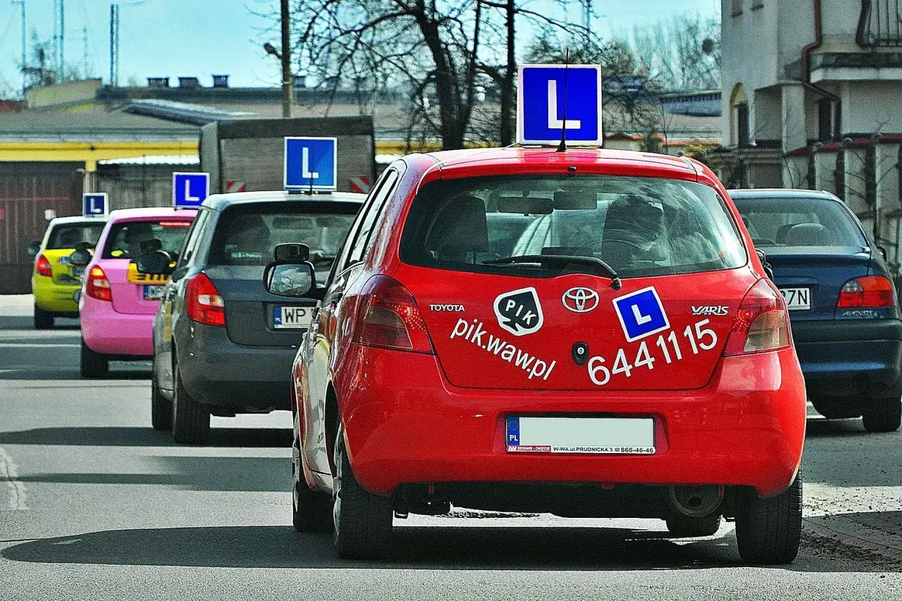 Czerwony samochód nauki jazdy z literą "L" na dachu. Zastanawiasz się, ile zarabia instruktor jazdy?