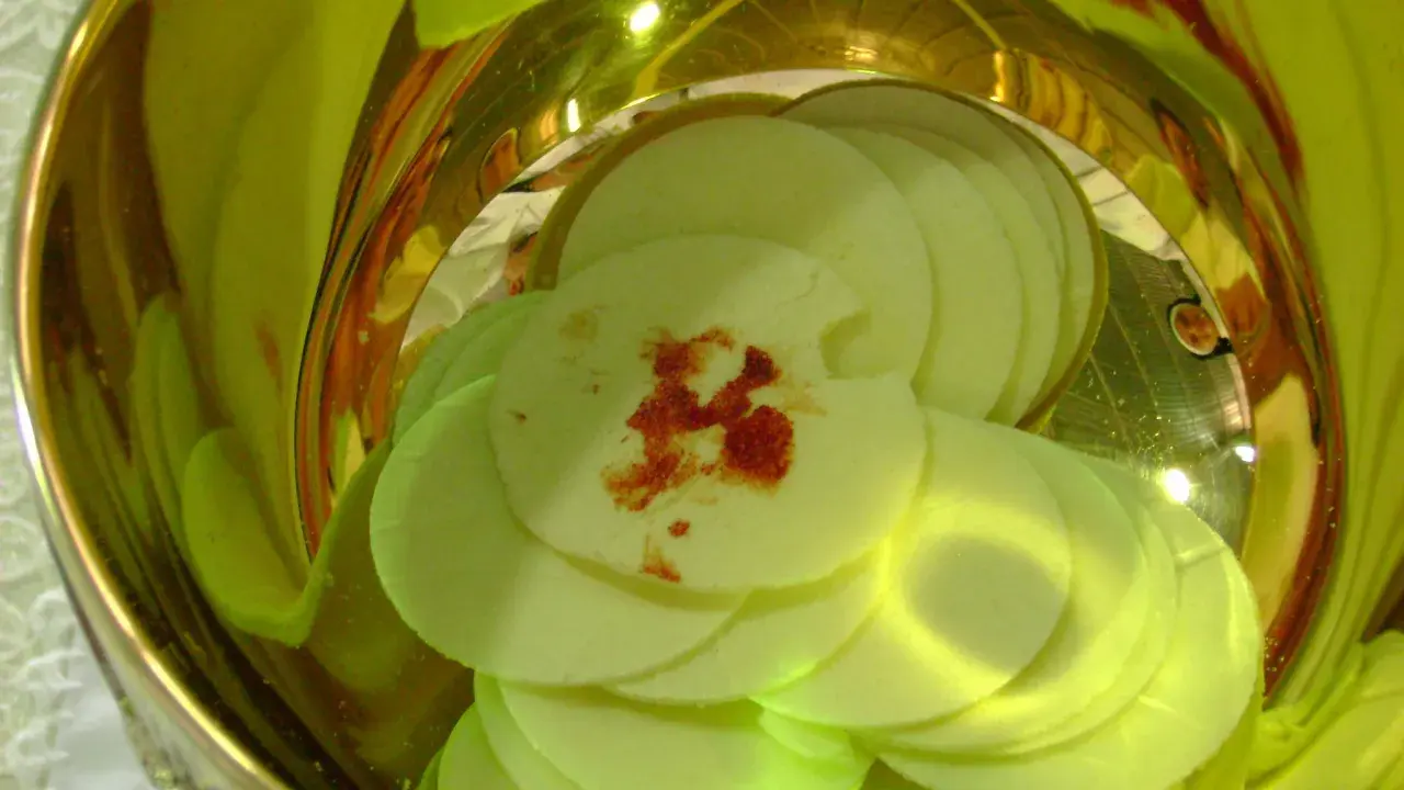 Hostie z plamą krwi, symbolizujące cud eucharystyczny w Indiach, w złotym naczyniu.