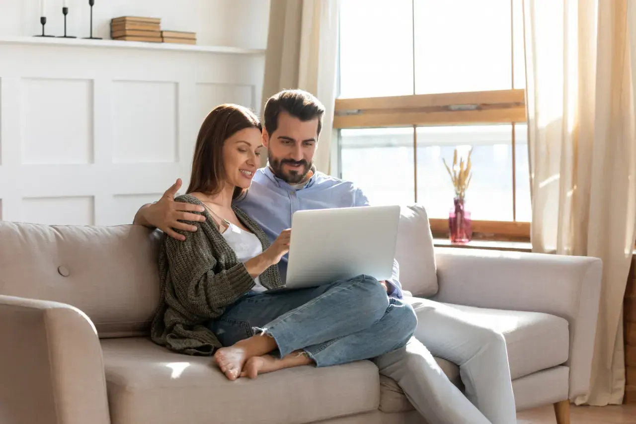 Couple planifiant l'amélioration de leur habitat, consultant un prêt sur leur ordinateur.