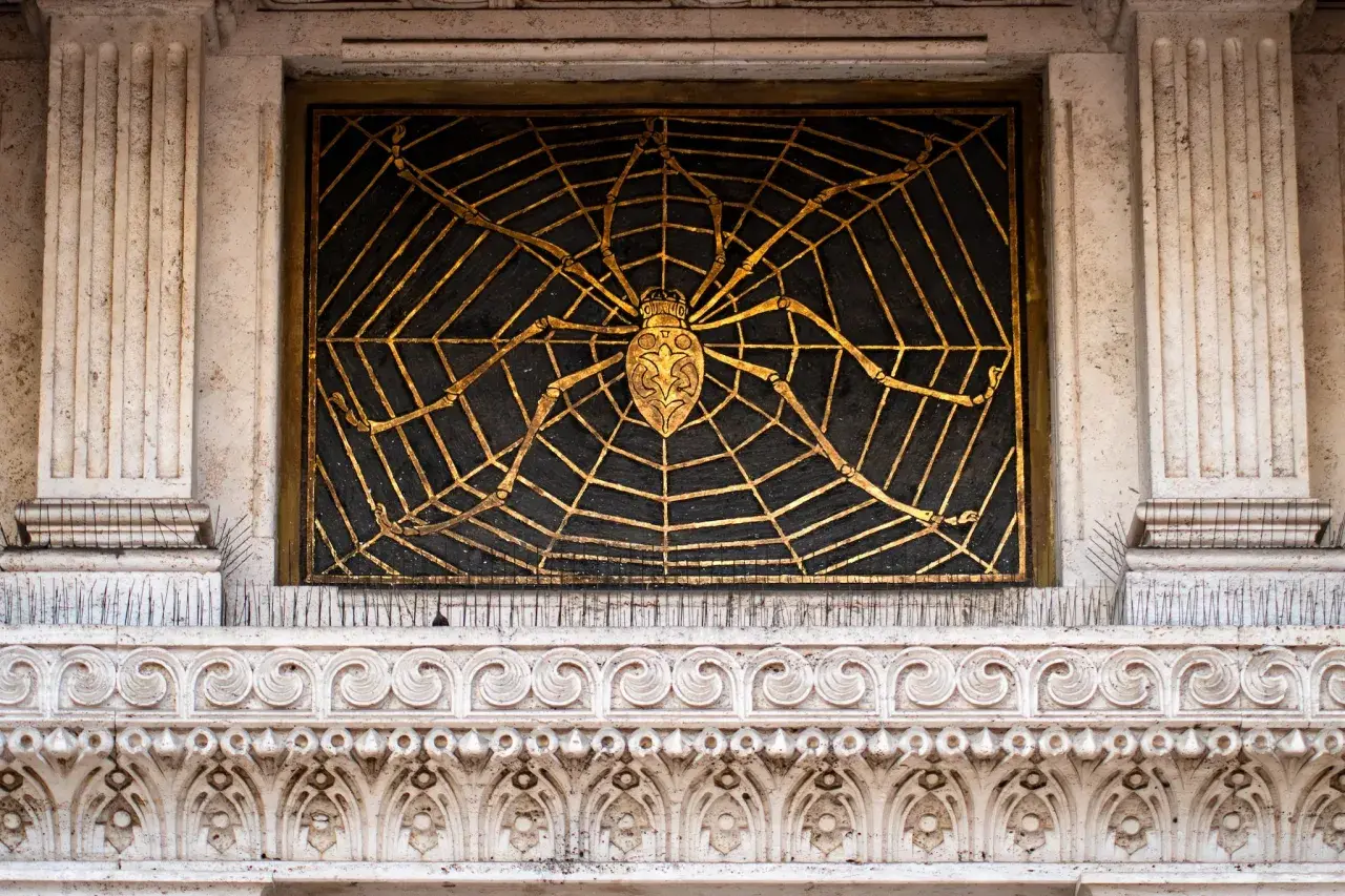 Ragno dorato su ragnatela nera, dettaglio architettonico del quartiere Coppedè interni.