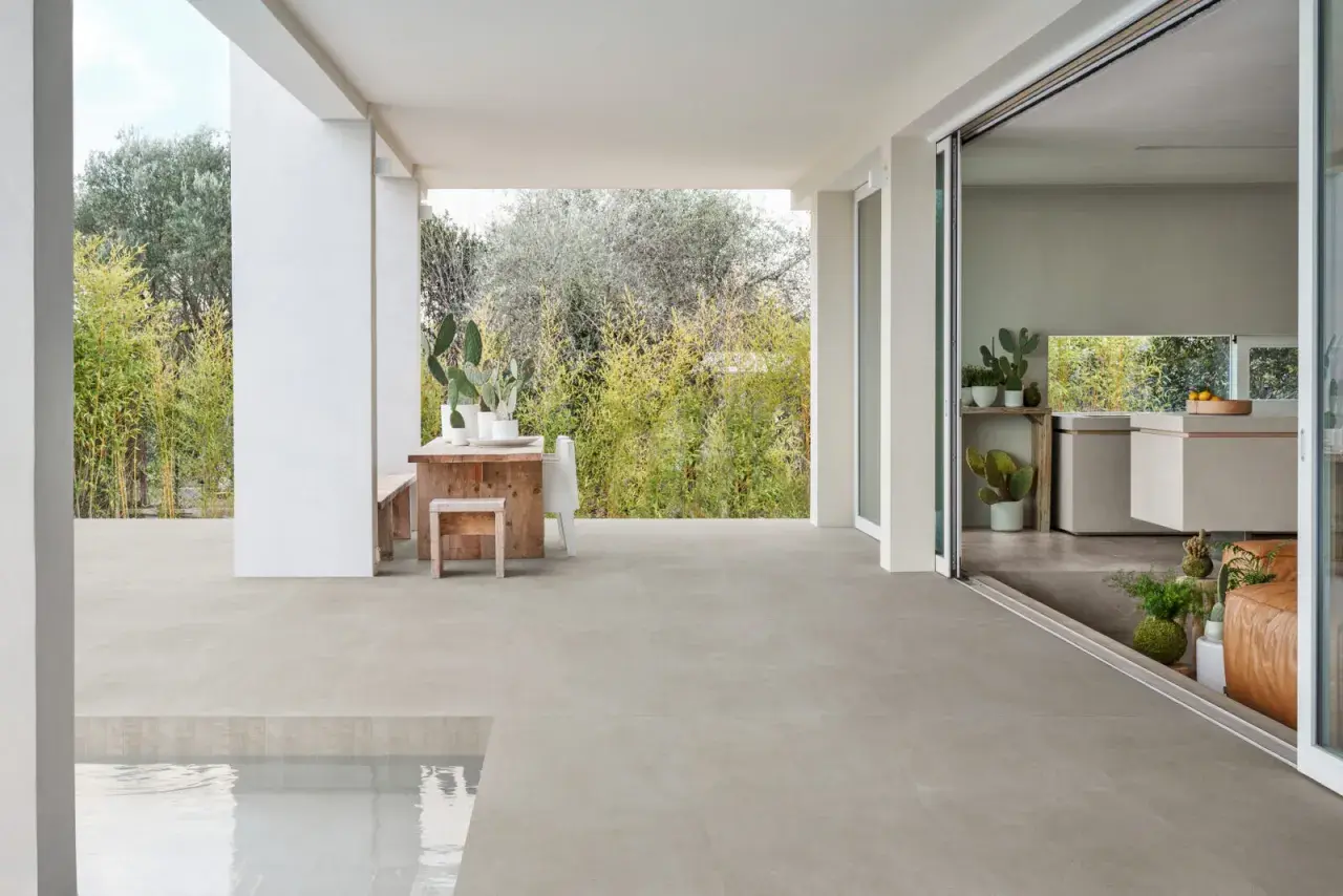 Terrazza con piscina e cucina moderna, pavimentata in gres materiale che si estende all'esterno.