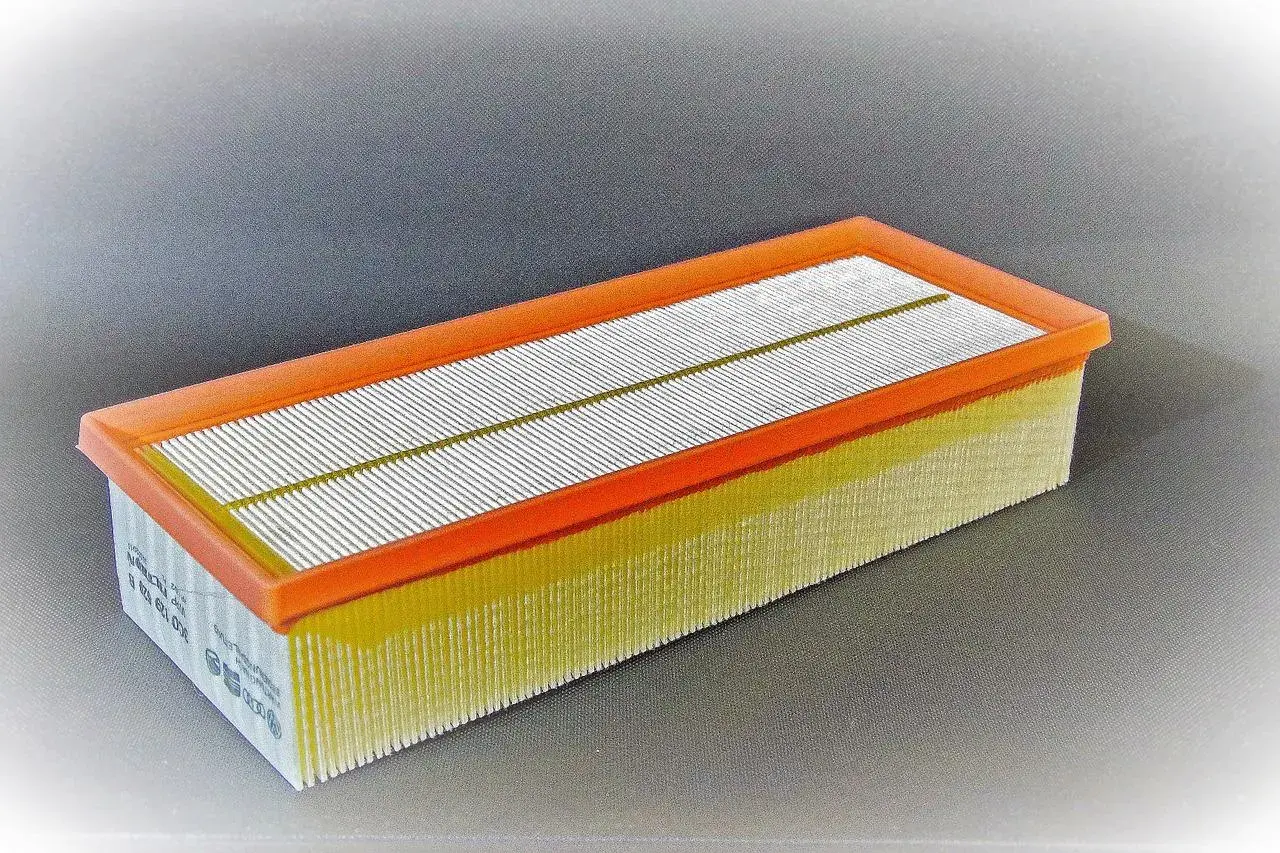 Filtro de aire rectangular con marco naranja y pliegues amarillos. Pregúntate cada cuanto se cambia filtro de aire para mantener tu motor limpio.