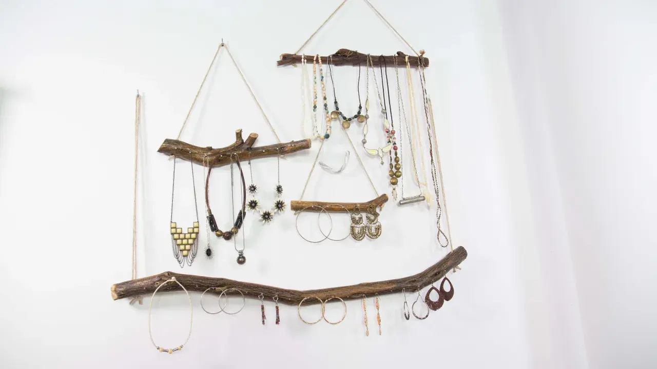 Colgante rústico con ramas de madera, ideal para exhibir collares y pendientes. Un ejemplo de manualidades de madera para adultos, con un toque bohemio.