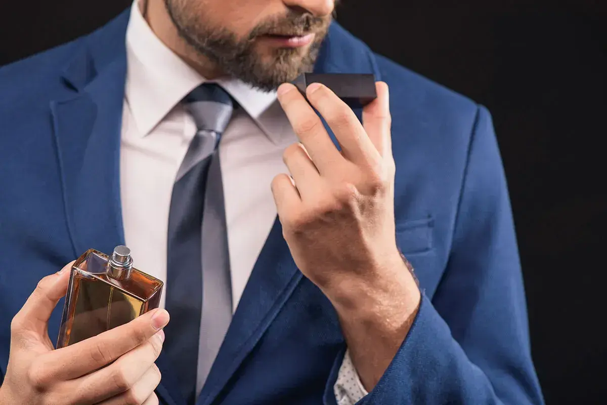 Elegancki mężczyzna w garniturze wącha perfumy. Czy to woda toaletowa czy perfumowana?