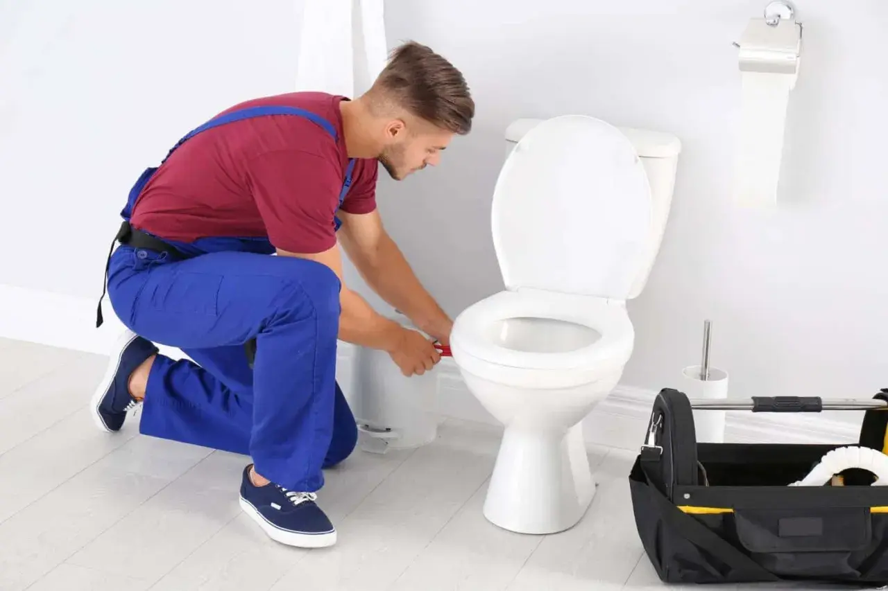 Idraulico al lavoro per sostituire guarnizione scarico WC. Attrezzi a portata di mano.