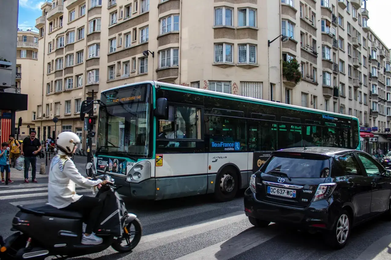 Paryż: autobus miejski i skuter na ulicy, symbolizujące dojazd do centrum z lotniska Charles de Gaulle.