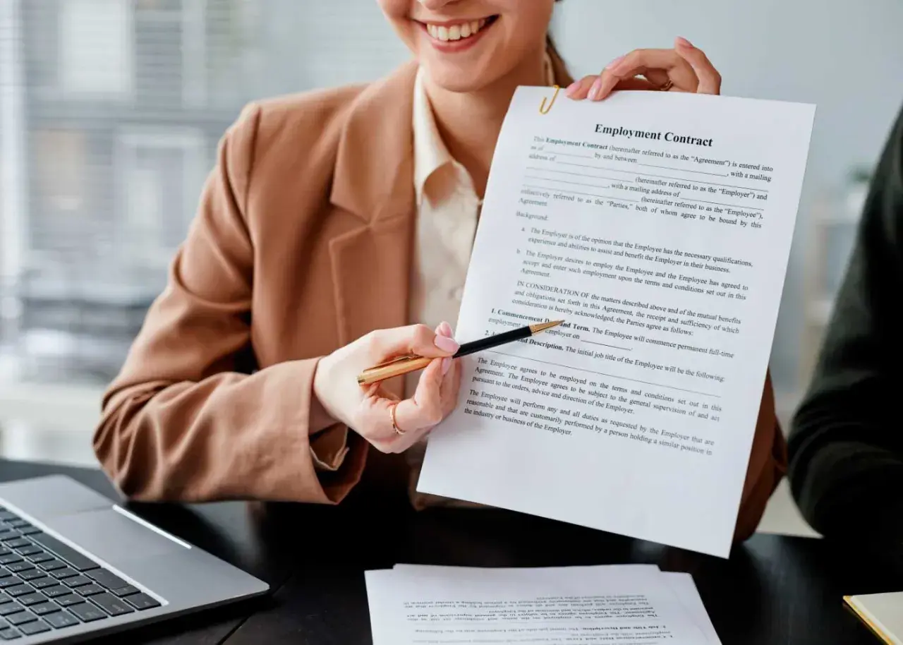Persona sonriente muestra un contrato de empleo, lista para firmar contrato.
