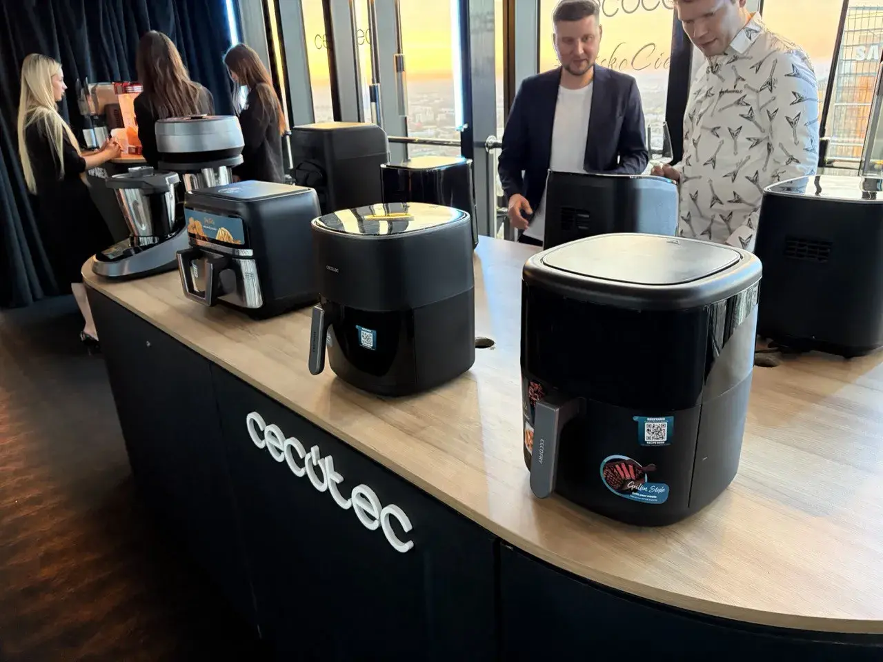 Prezentacja urządzeń kuchennych marki Cecotec. Na ladzie stoją frytkownice beztłuszczowe i robot kuchenny.