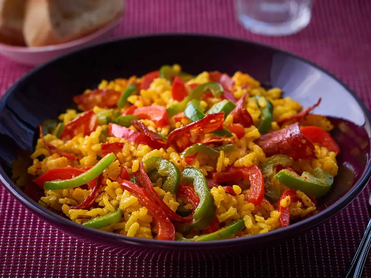 Un plat appétissant de riz à l'espagnol, garni de poivrons rouges et verts, et de chorizo.