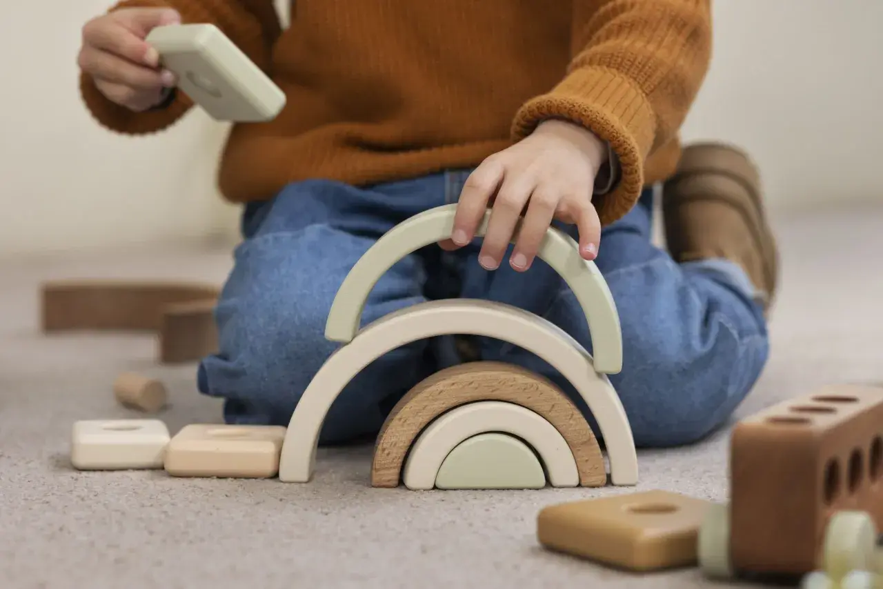 Niño jugando con bloques de madera, creando un arcoíris. Un ejemplo del sistema montessori para el desarrollo infantil.