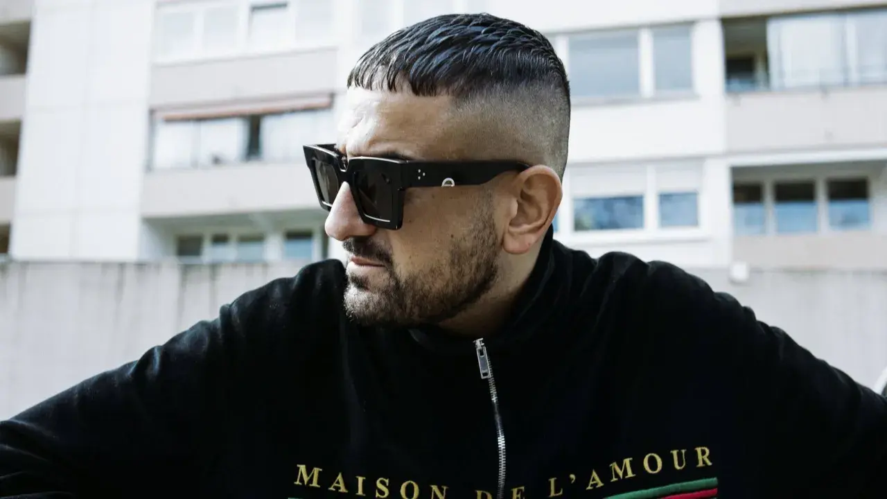 Ein Mann mit kurzgeschorenem Haar und Sonnenbrille, der die Rap-Szene repräsentiert.