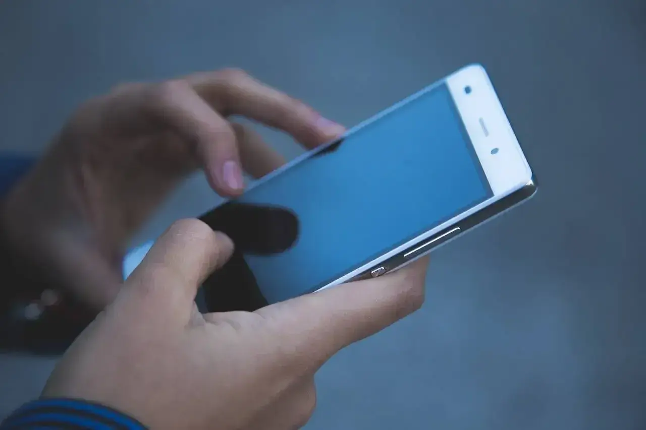 Dłonie trzymające smartfon. Zastanawiasz się, jak odzyskać telefon zatrzymany przez policję?