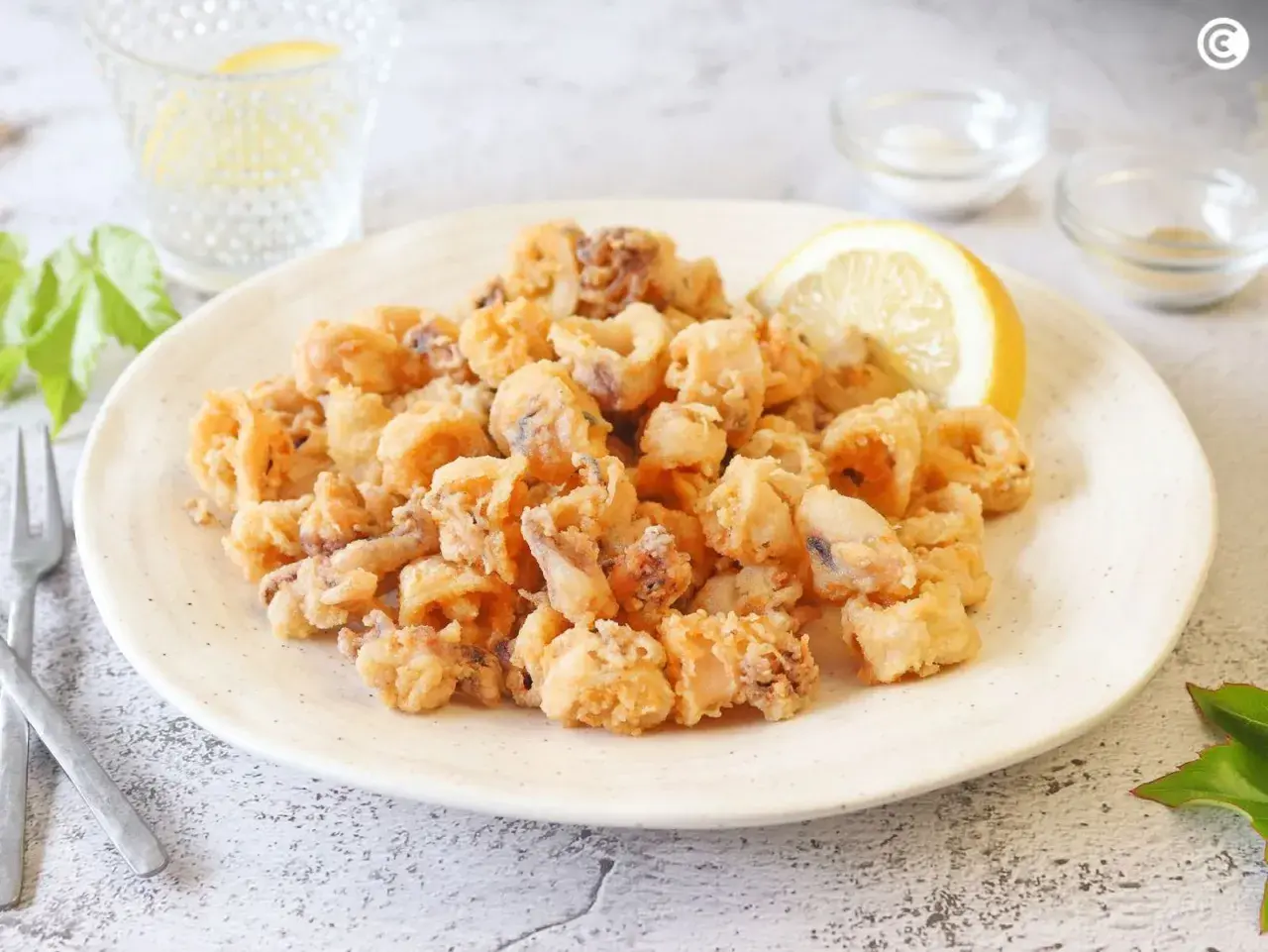 Un plato generoso de chipirones fritos crujientes, adornado con una rodaja de limón.