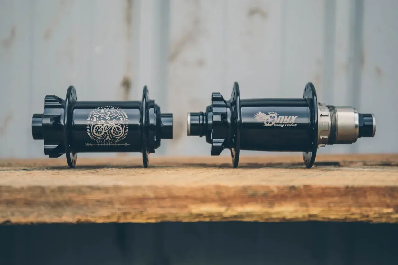 Two black Onyx Vesper hubs, one with a skull and bike graphic, the other with the Onyx logo, ready for a review.