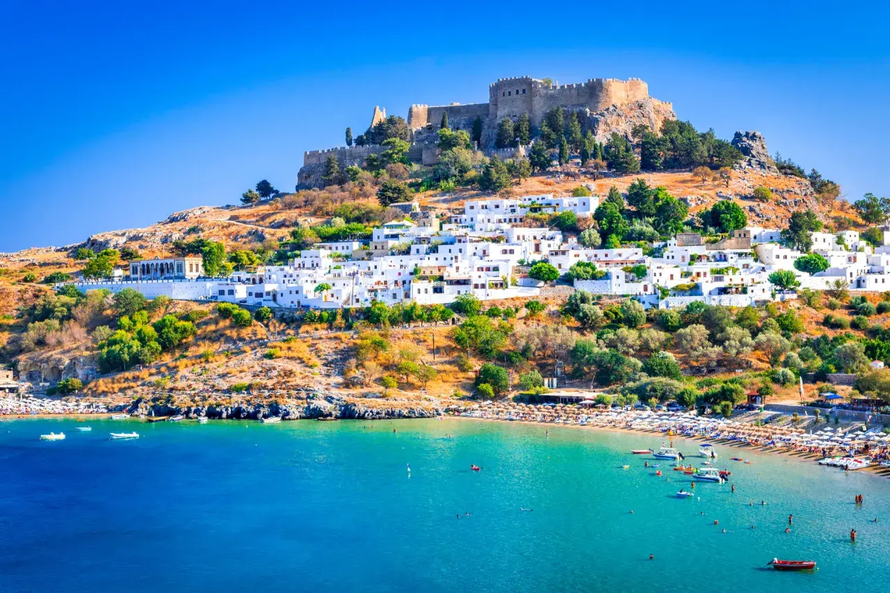 Lindos auf Rhodos: weiße Häuser, Burgruine und ein belebter Strand. Tolle Rhodos Urlaub Tipps für deine Reise!