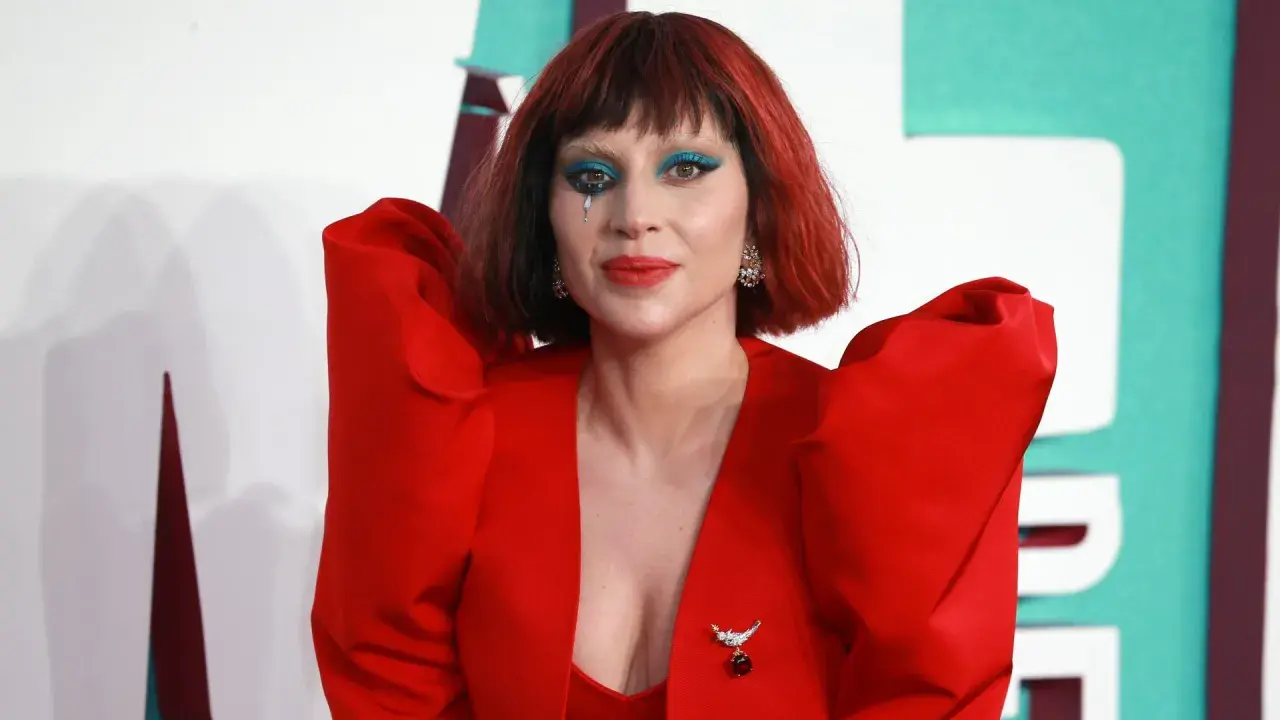 Lady Gaga w czerwonym, teatralnym stroju z niebieskim makijażem oczu i łzą na policzku. Fani marzą o koncercie Lady Gaga w Polsce.