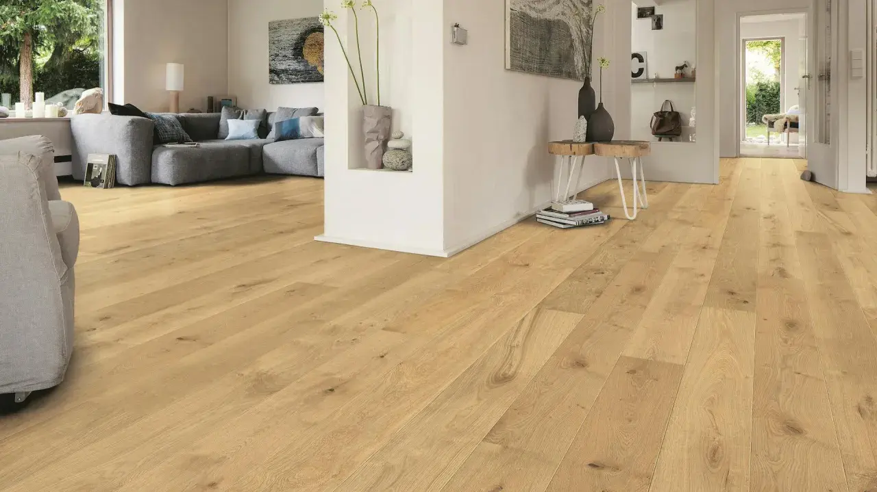 Un soggiorno moderno con parquet chiaro. Un divano grigio e un tavolino completano l'arredamento. Immagine che illustra come si monta il parquet.