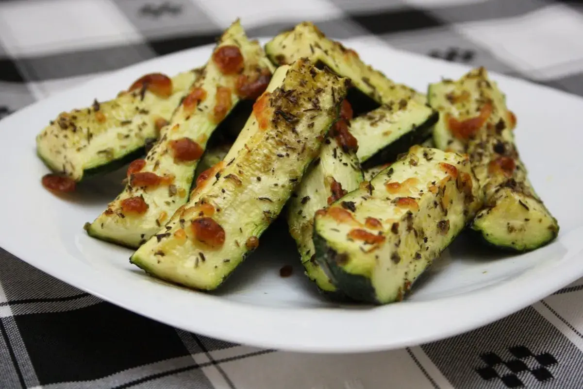 Delicioso calabacín al horno, cortado en bastones y cubierto con queso derretido y hierbas aromáticas.
