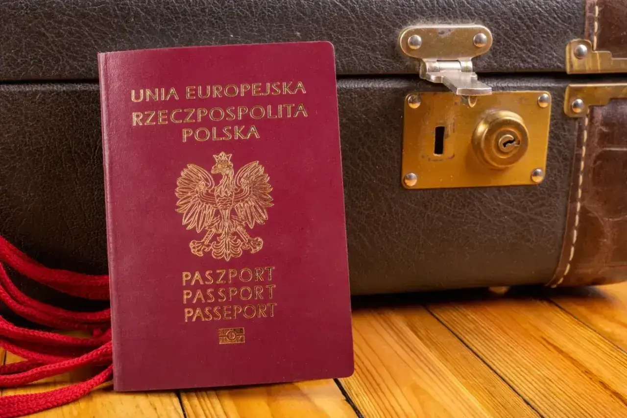 Czerwony paszport RP i stara walizka. Czy do Czarnogóry potrzebny jest paszport? Tak, ten dokument jest niezbędny do podróży.