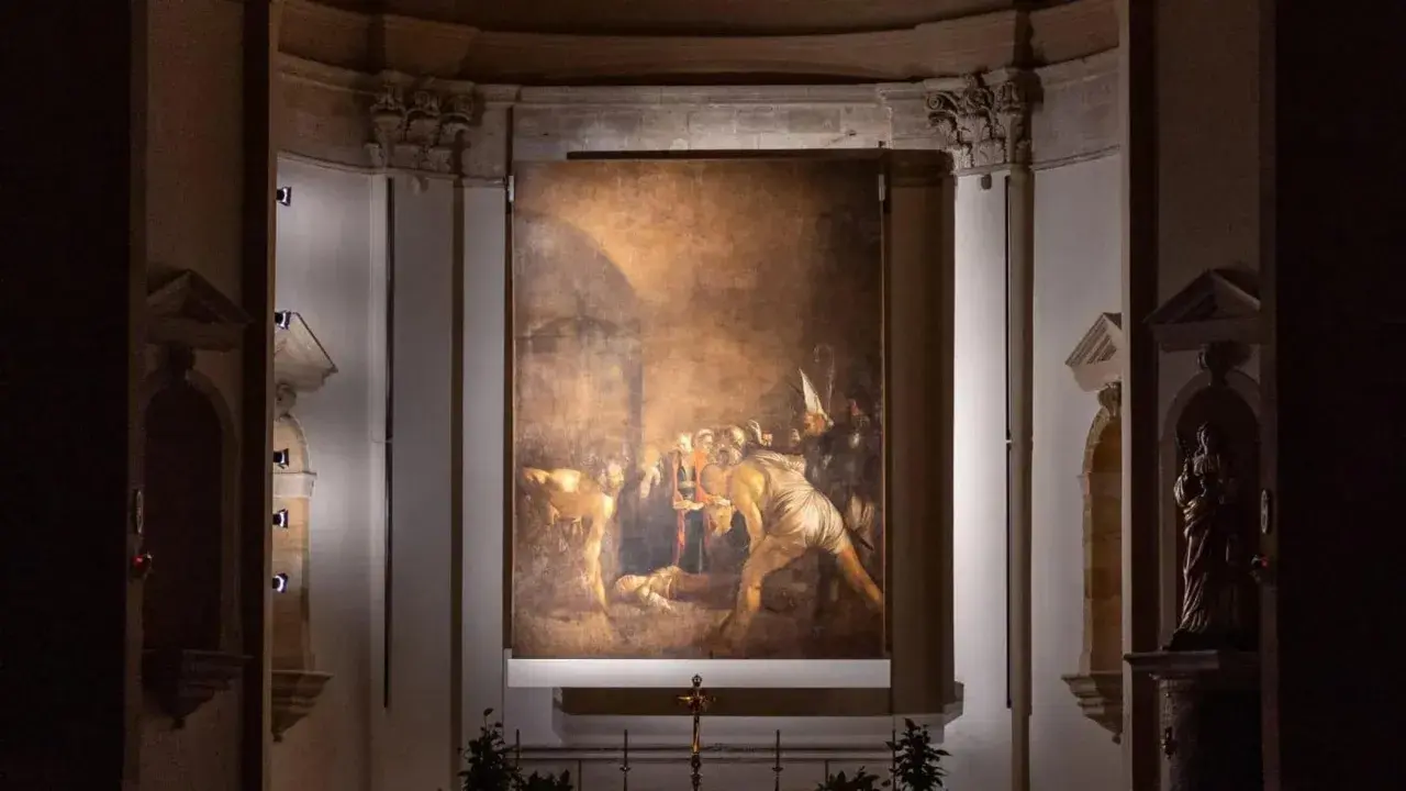 Il Seppellimento di Santa Lucia, capolavoro di Caravaggio in Sicilia, illuminato nell'oscurità di una chiesa.