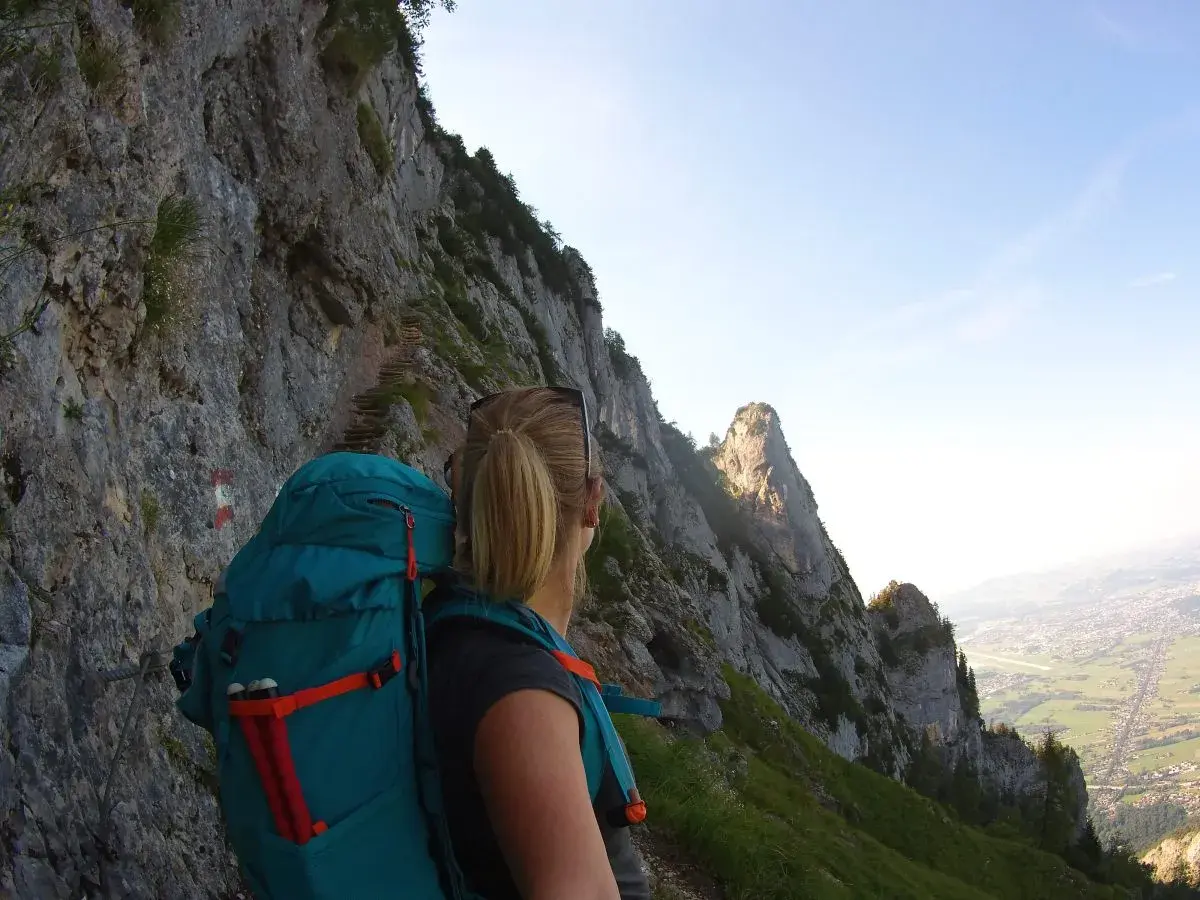 Wanderin auf dem Salzburger Hochthron, mit Blick auf steile Felsen und das Tal.