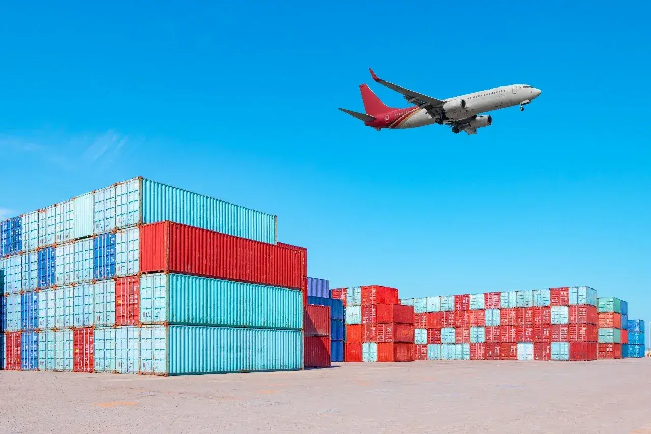 Frachtflugzeug über Containerstapeln. Die IATA Bedeutung für globalen Handel wird hier visuell dargestellt.