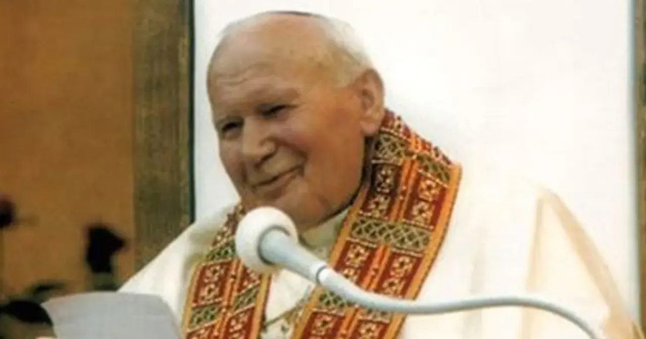 Jan Paweł II z uśmiechem przemawia do wiernych, trzymając w ręku tekst. Jego barki zdobi ozdobna stuła.
