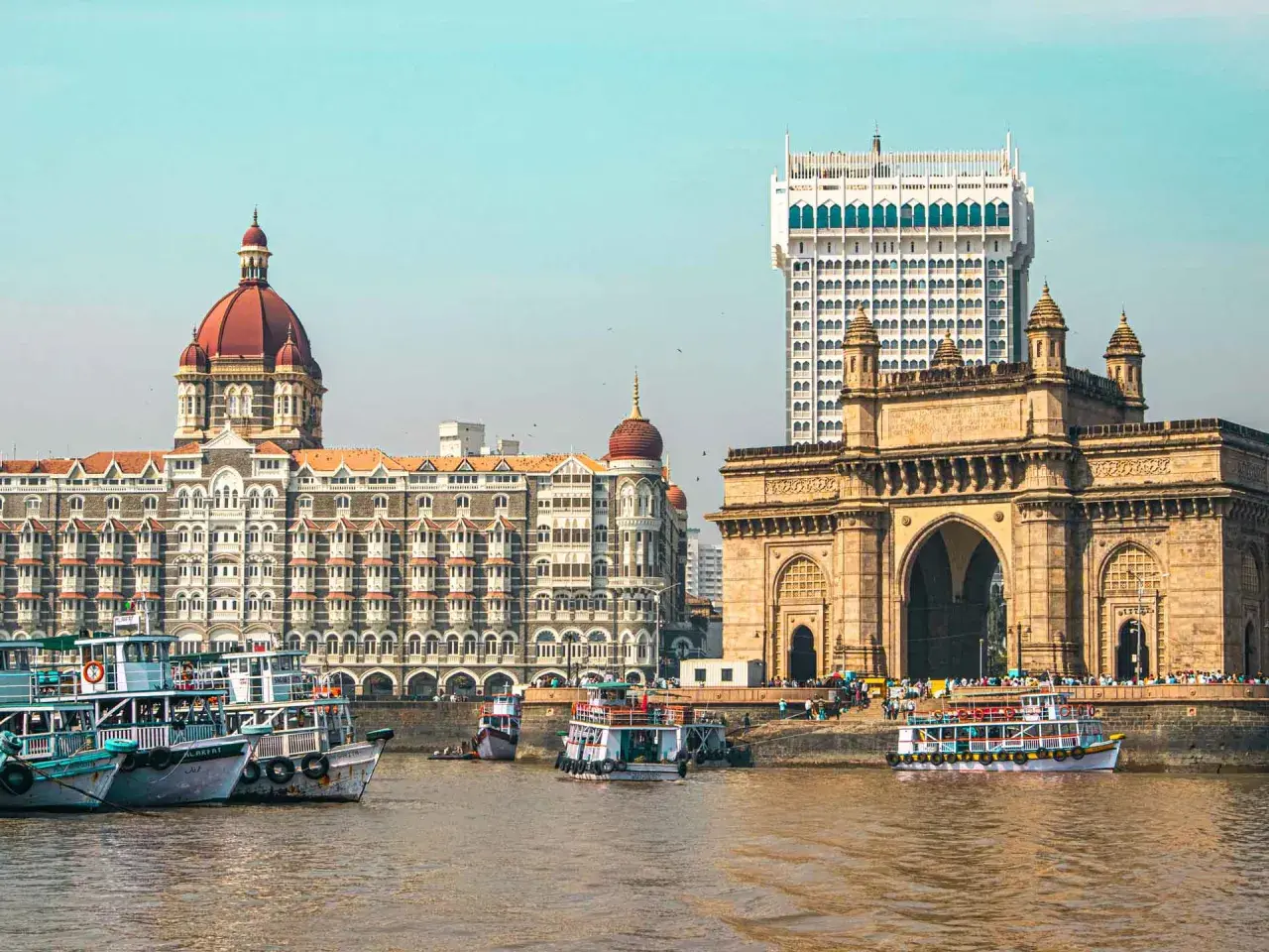 Brama Indii i hotel Taj Mahal Palace w Mumbaju, Indie. Wokół pływają łodzie.