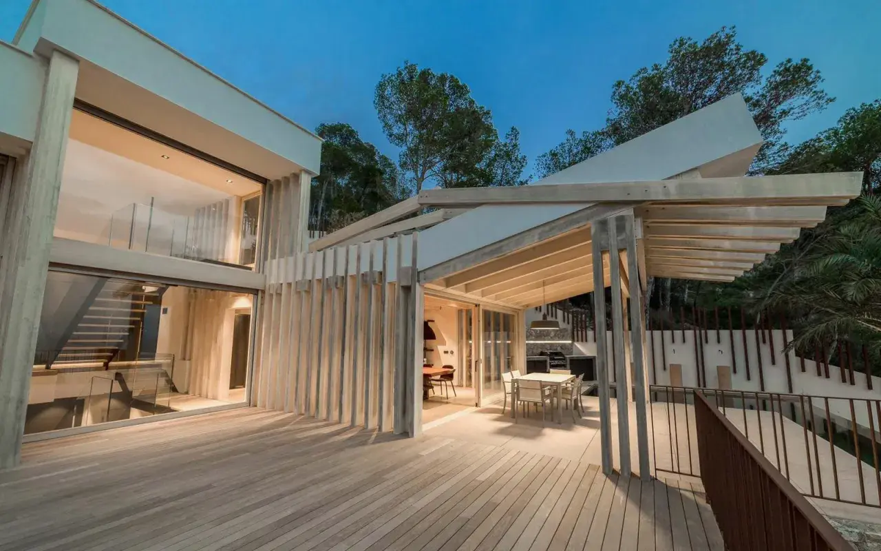 Terraza moderna con suelo de madera Accoya, pérgola y fachada acristalada.