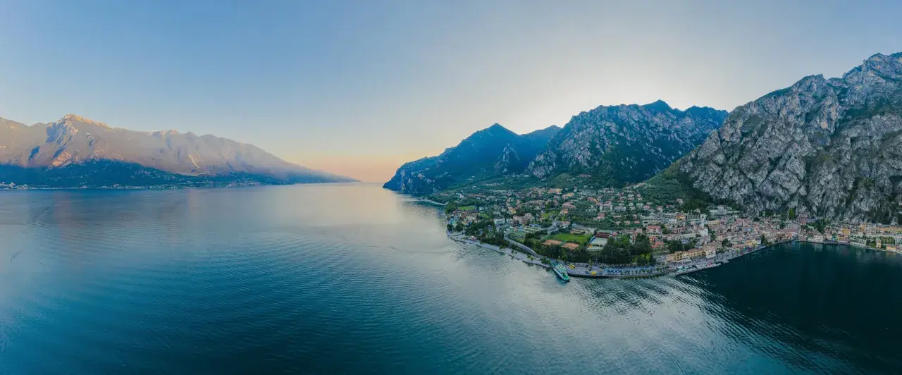 Panoramica del Lago di Garda con montagne imponenti e una città pittoresca. Perfetto per scoprire le **Unternehmungen Gardasee**.