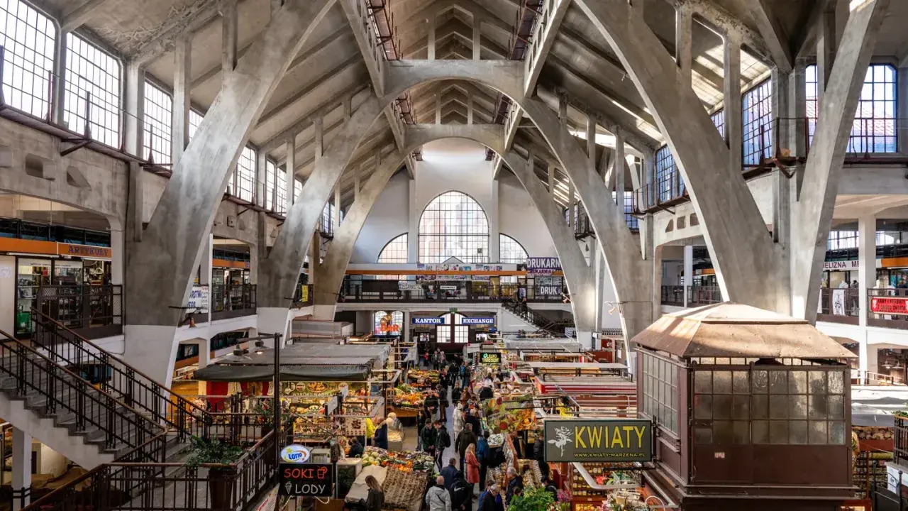 Das Innere der Markthalle, ein Wahrzeichen von Wrocław, mit seinen beeindruckenden Betonbögen und dem lebhaften Treiben der Marktstände.