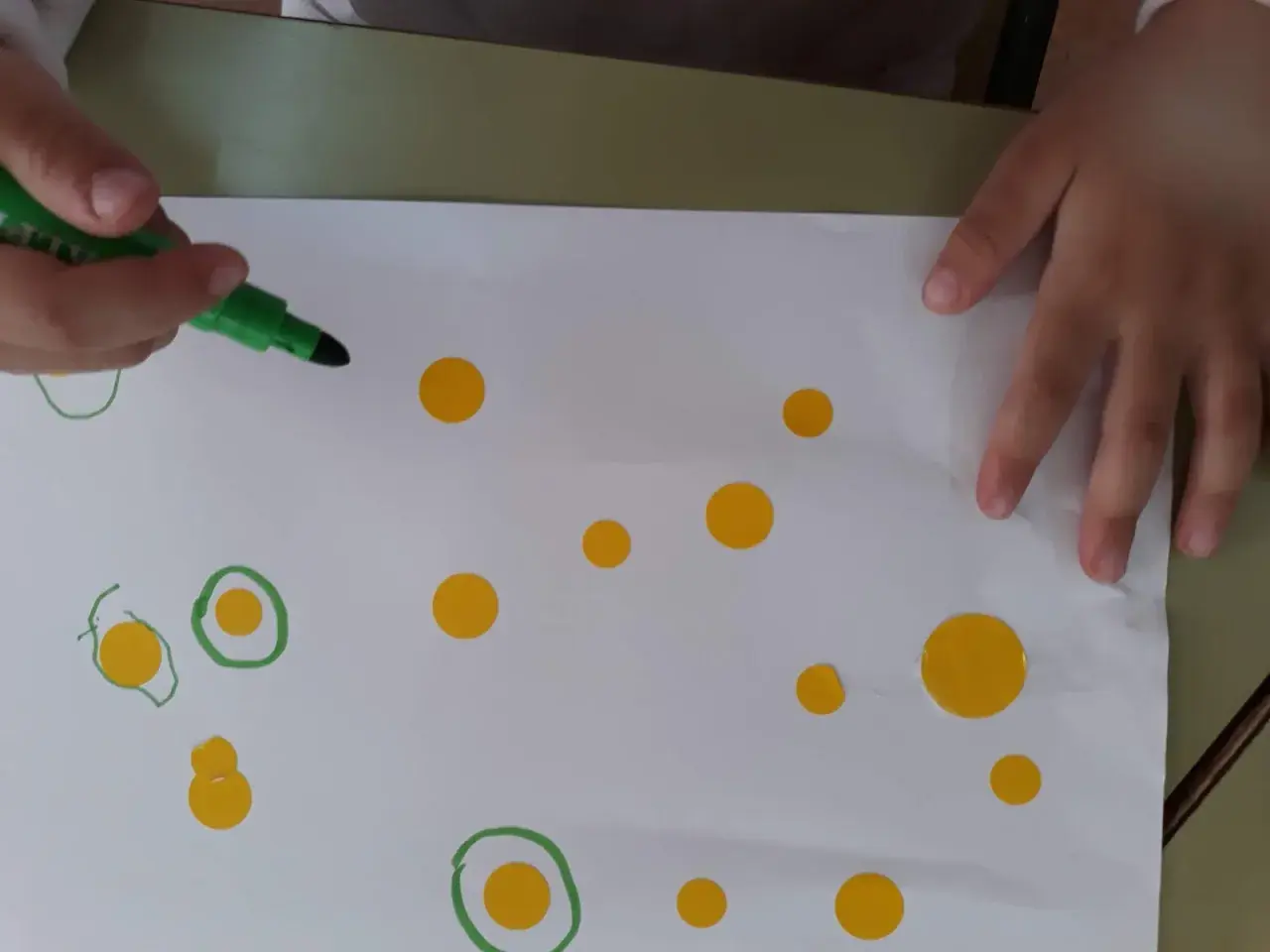 Manos de niño creando círculos y puntos, inspirándose en las kandinsky obras para niños.